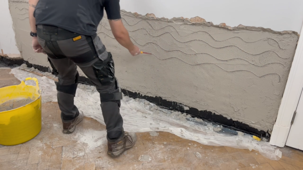 Scratching up the first coat of damp resistant plaster